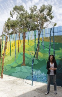 María Ortega junto a su mural “Viajando el Paraíso: UPO”