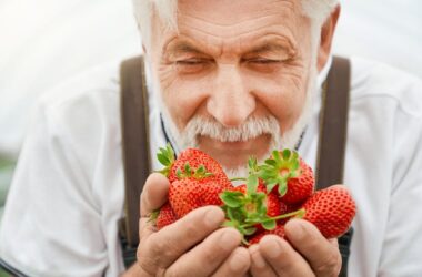 Hombre de edad avanzada olfatea unas fresas