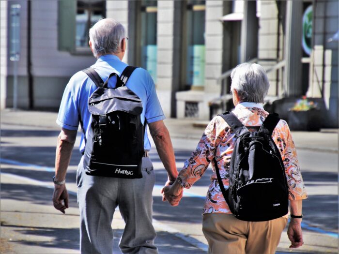 Una pareja de personas mayores pasean por una calle