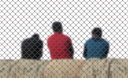 Migrantes de espaldas tras una valla