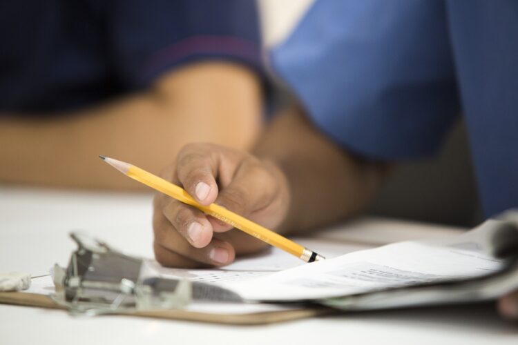 Imagen detalle del brazo de un médico con lápiz y papeles en un escritorio